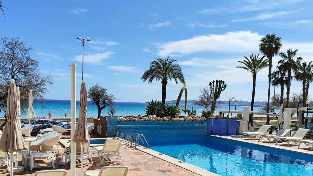 a swimming pool with chairs and the ocean in the background at BLUESEA Anba Romaní in Cala Millor