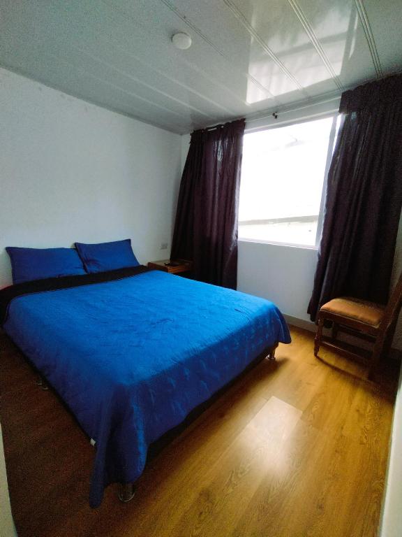 a bedroom with a blue bed and a window at Bohemia Hotel in Tunja