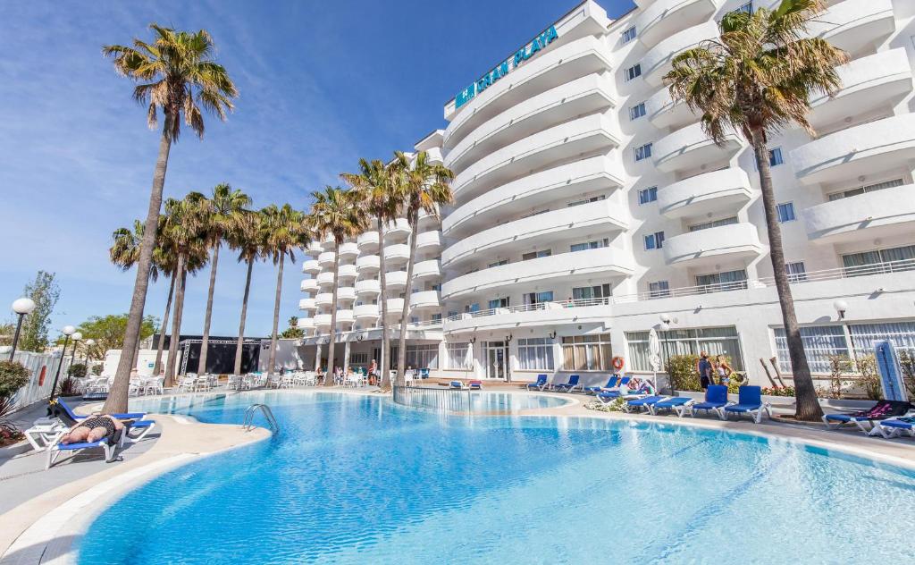 una piscina di fronte a un hotel con palme di BLUESEA Gran Playa a Sa Coma