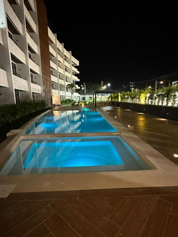 a large swimming pool with blue water at night at QUEEN ANGEL condo in Cozumel