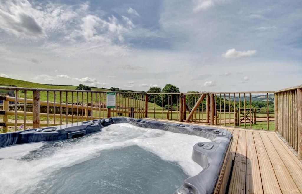 a hot tub on a deck with a fence at 1 Bed in Tiverton oc-work in Bampton