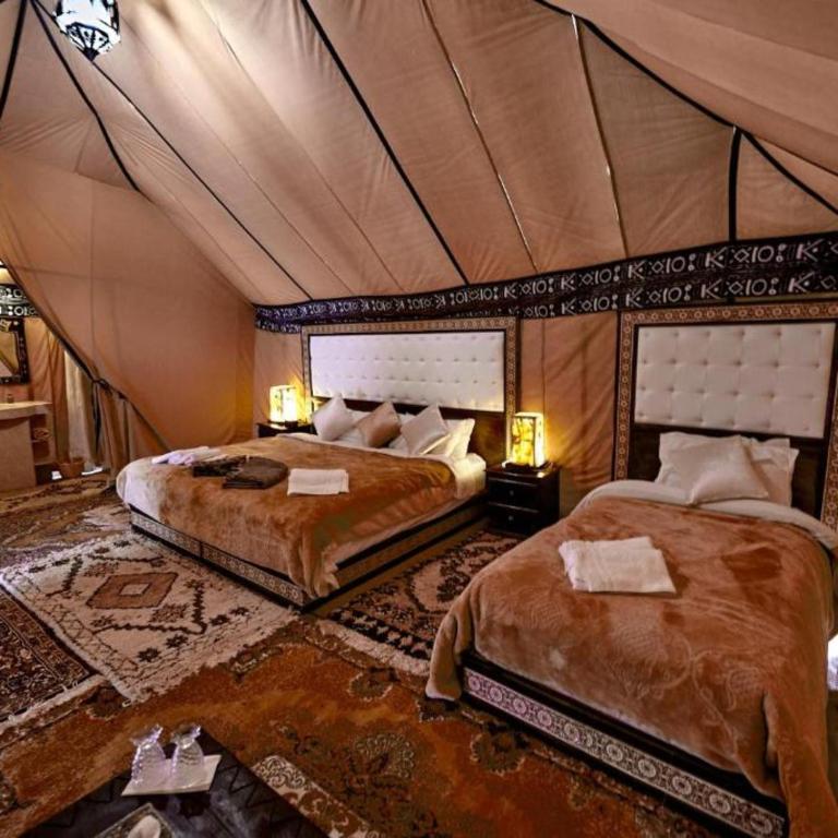 a bedroom with two beds in a tent at Overnight Luxury Camp in Merzouga