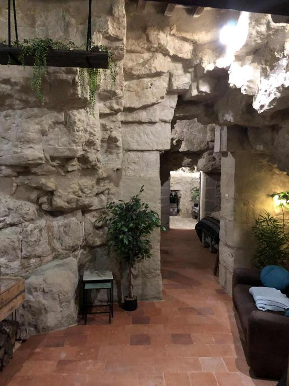 a stone wall with a couch and a plant in a room at TROGLODYTE - La Grotte d'Auré in Le Puy-Notre-Dame