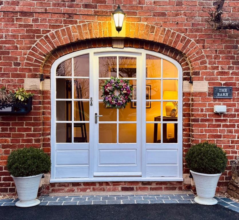 a white door on a brick building with two plants at The Barn, Boutique Self-Catering Apartment - Belvoir Suite in Allington