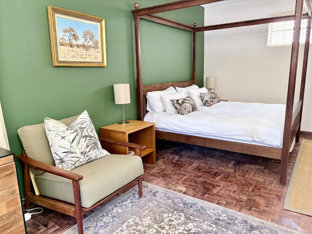 a bedroom with a canopy bed and a chair at Oatlands Cottages in Grahamstown