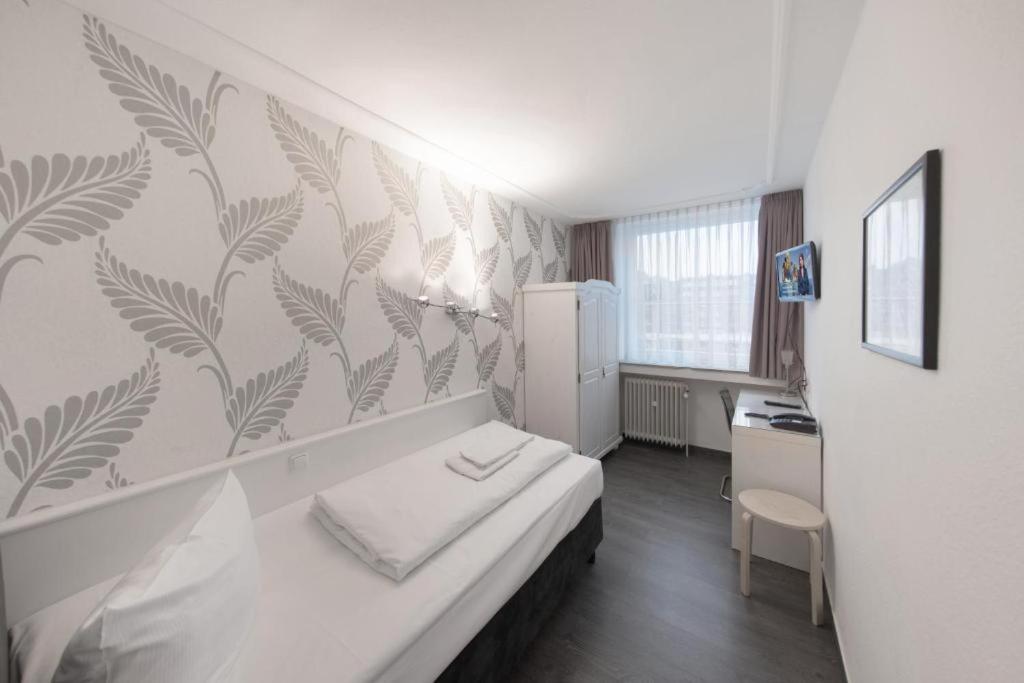 a small room with a bed and a refrigerator at Aachener Stadthotel in Aachen