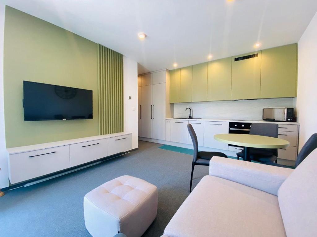 a living room with a table and a tv and a kitchen at Apartman Alex in Liptovský Mikuláš