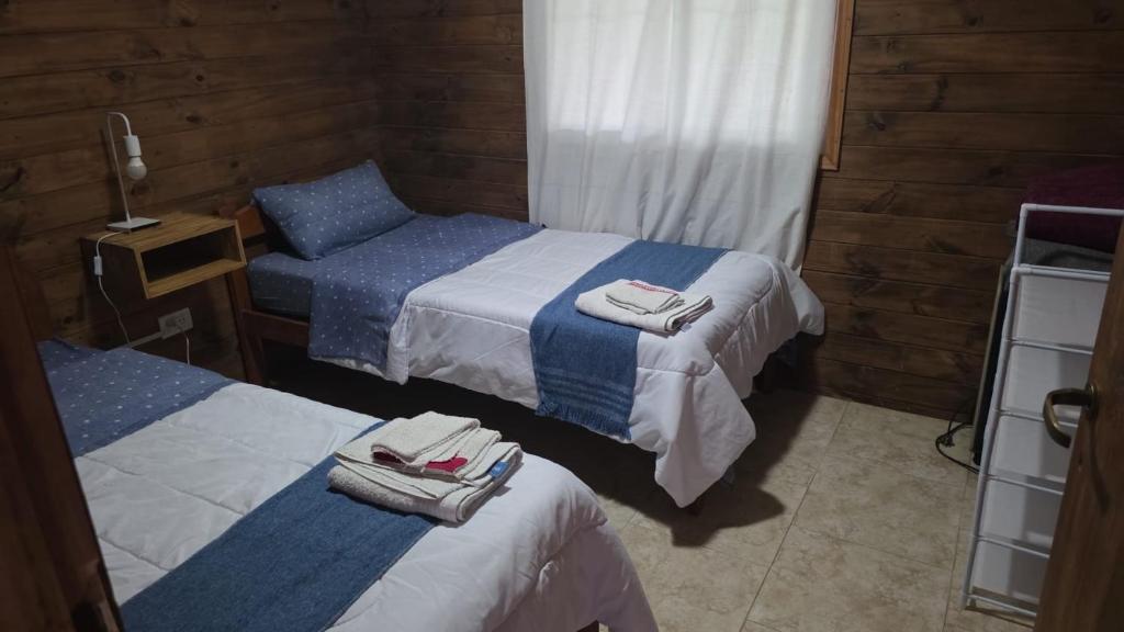 two beds in a room with towels on them at Cabaña la Relajación in San Miguel del Monte