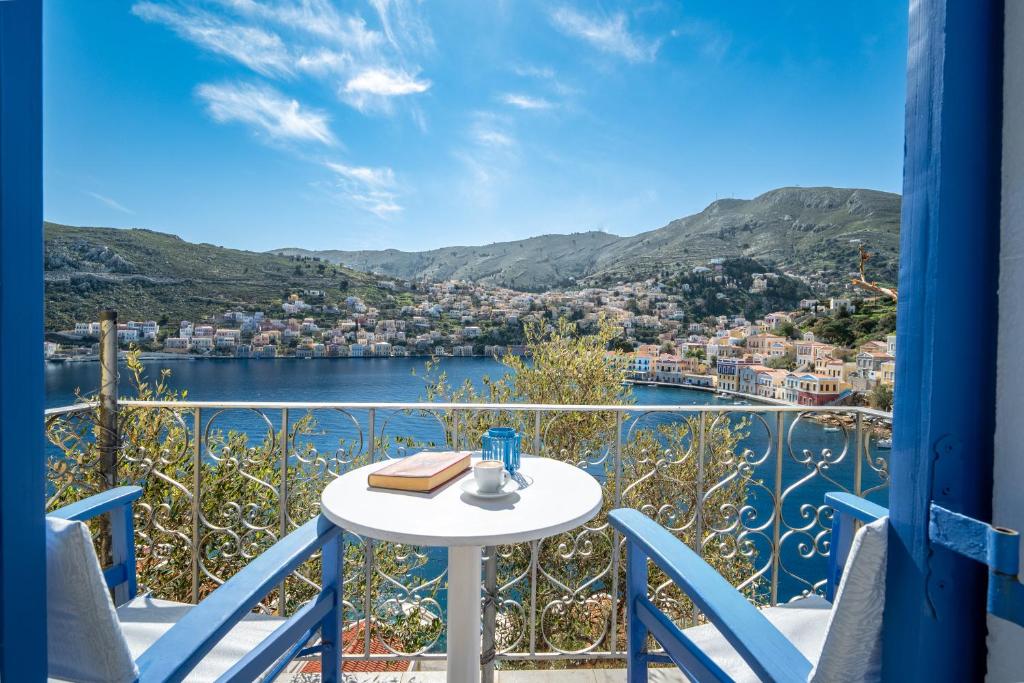 ein Balkon mit Tisch und Blick aufs Wasser in der Unterkunft Artiki's Studios - Sea & Harbour View Apartments in Symi in Symi