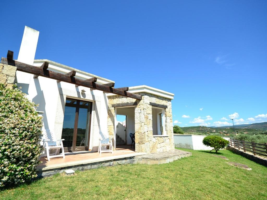 mały kamienny dom z dwoma krzesłami na trawniku w obiekcie Belvilla by OYO Vista Blu Resort Villa Otto Pax w mieście Alghero
