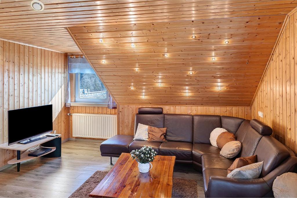 a living room with a leather couch and a tv at Fewo Tanja's Blumenparadies in Hollfeld