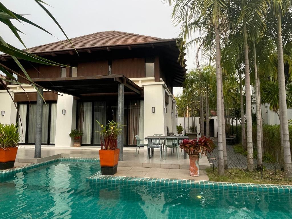 a swimming pool in front of a house with palm trees at Pool Villa PB6rayong in Rayong