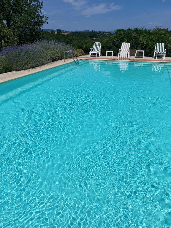 a large swimming pool with two white chairs in it at Valdichiana Panorama Villa - Private Pool in Marciano
