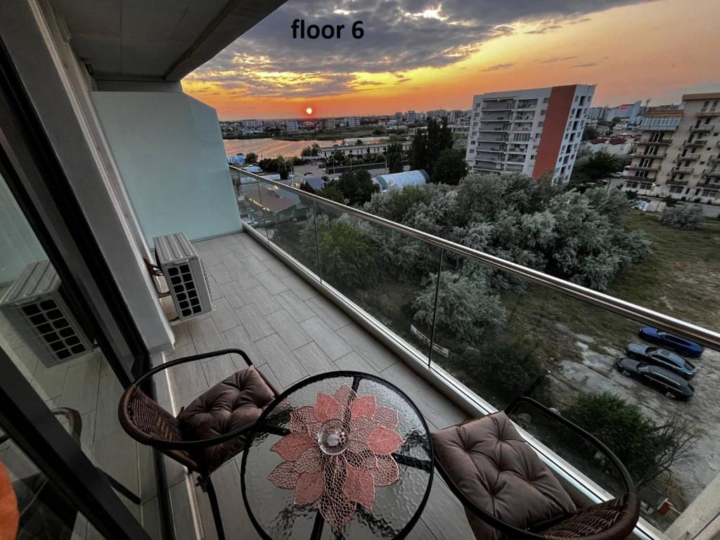 a balcony with a table and chairs and a sunset at Mamaia Sea Vibe in Mamaia Sat/Năvodari