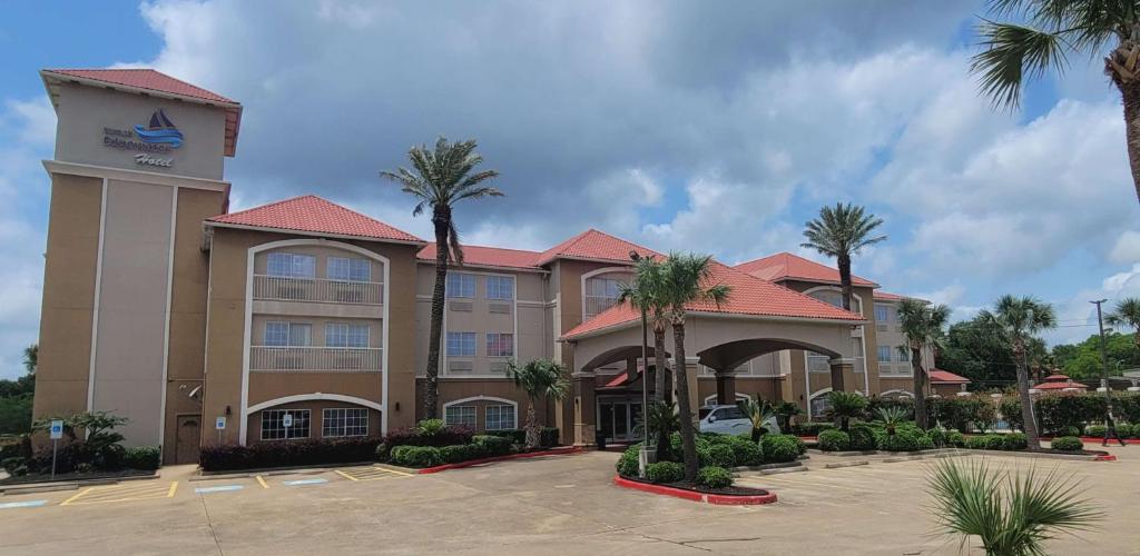 a hotel with palm trees in a parking lot at Kemah Edgewater Hotel, SureStay Collection by Best Western in Seabrook