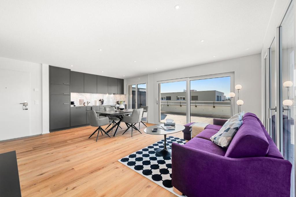 a living room with a purple couch and a table at Penthouse Exclusif - Grande Terrasse - Avenches - Self Check-in in Avenches