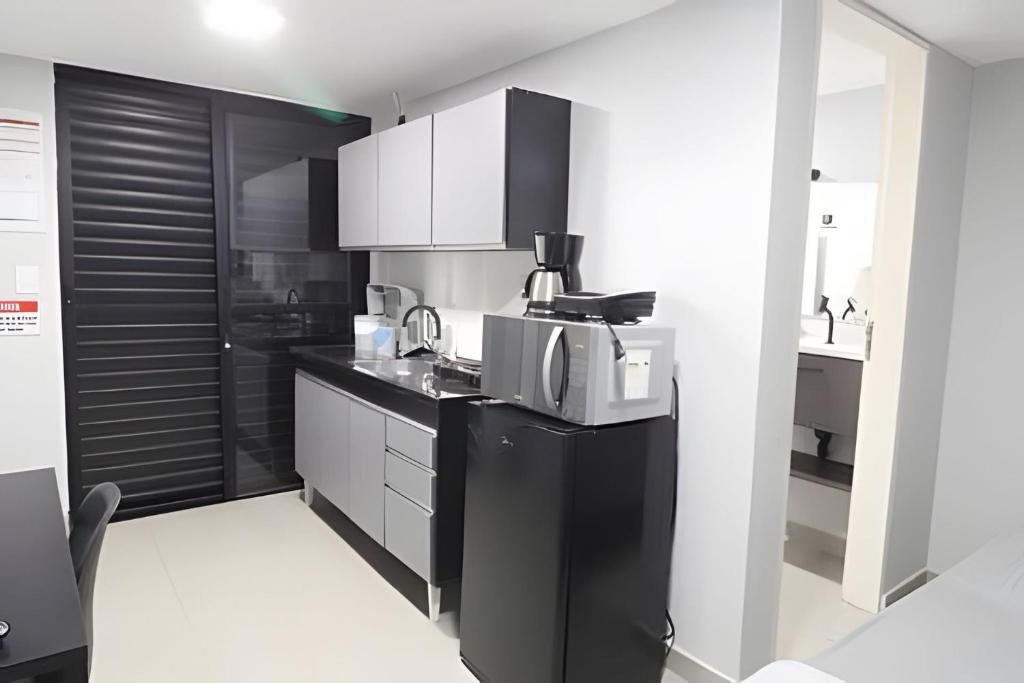 a kitchen with black and white cabinets and a microwave at Studio VI - Com Ar Condicionado in Jundiaí