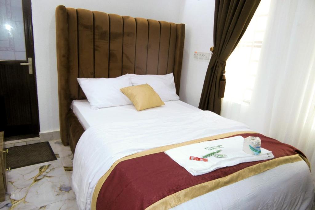 a bedroom with a bed with a large wooden headboard at Dawn Emeka Hotels in Akwa