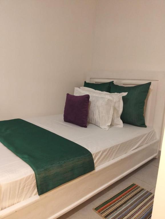 a bed with green and white pillows on it at Imperial cabins in Nyeri
