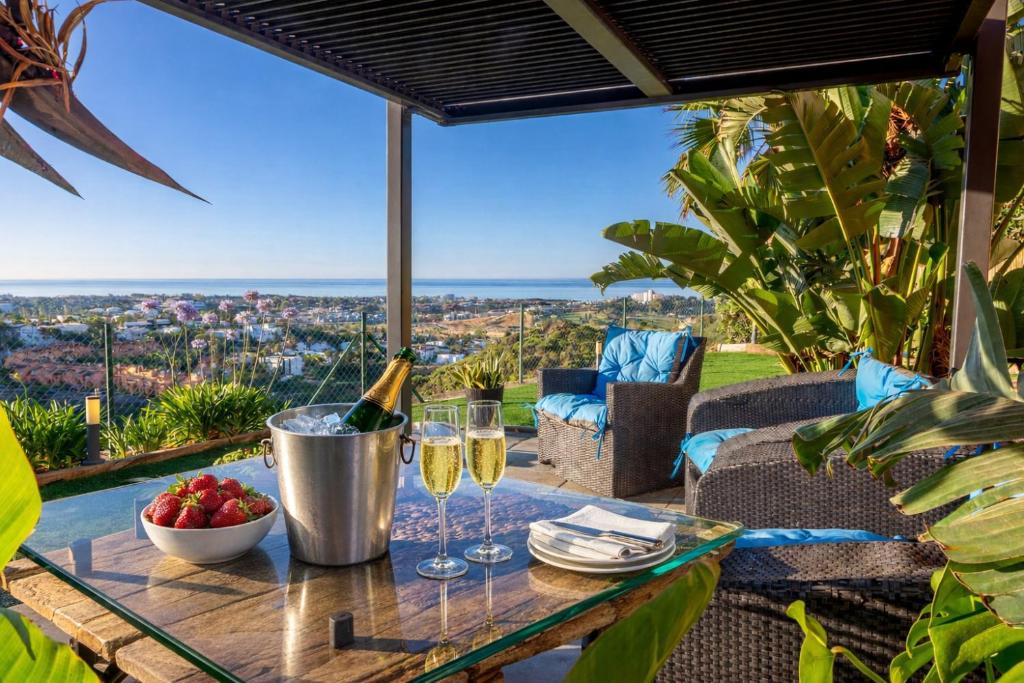 a table with wine glasses on a balcony with a view at Alta Luminara Boutique Residence Sea View Terraces Marbella Hills in Benahavís