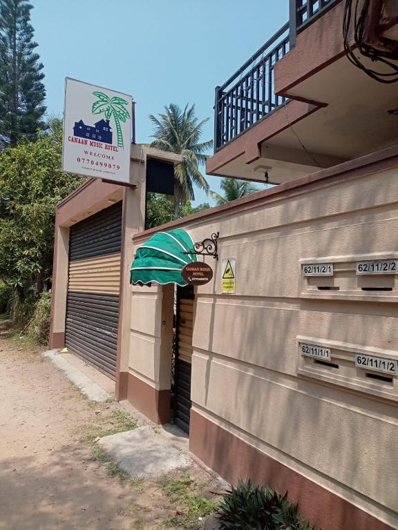 a building with a green umbrella next to a garage at CANAAN MUSIC Hotel in Moratuwa