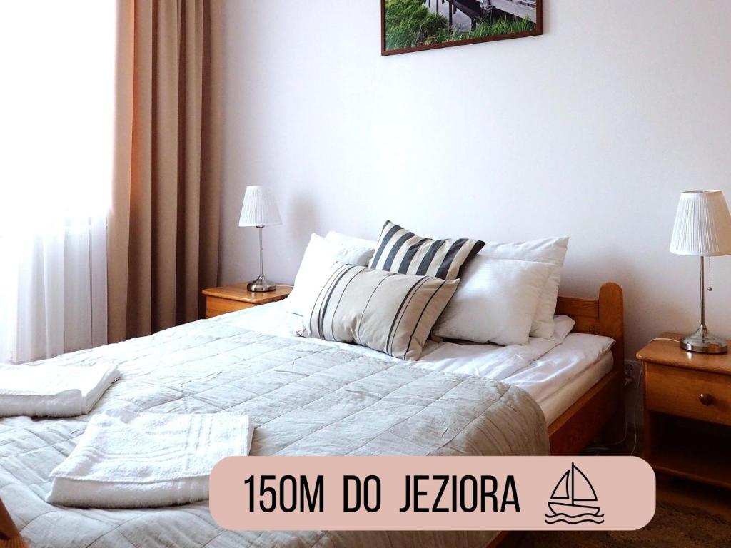 a bedroom with a bed with white sheets and pillows at Apartamenty Vega in Charzykowy