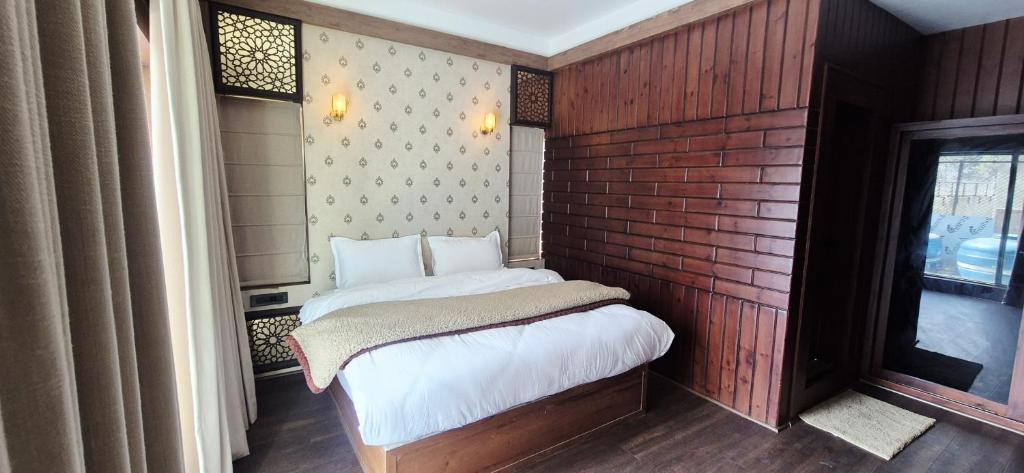 a small bed in a room with a brick wall at Pine Breeze Luxe in Gulmarg