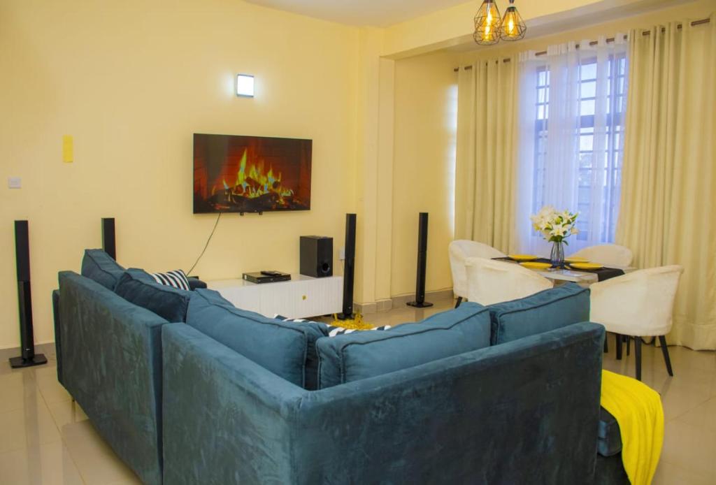 a living room with a blue couch and a tv at Mystic cabins in Nyeri