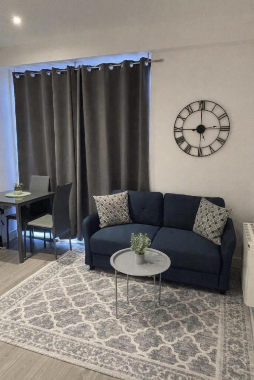 a living room with a blue couch and a clock at 6 Aviv Place in Addlestone