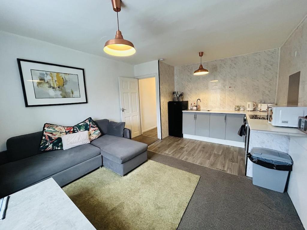 a living room with a couch and a kitchen at Cosy Flat - Over Arch in Oswaldtwistle