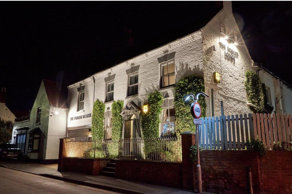 a white brick house with ivy growing on it at night at The Forest Lodge in Edwinstowe