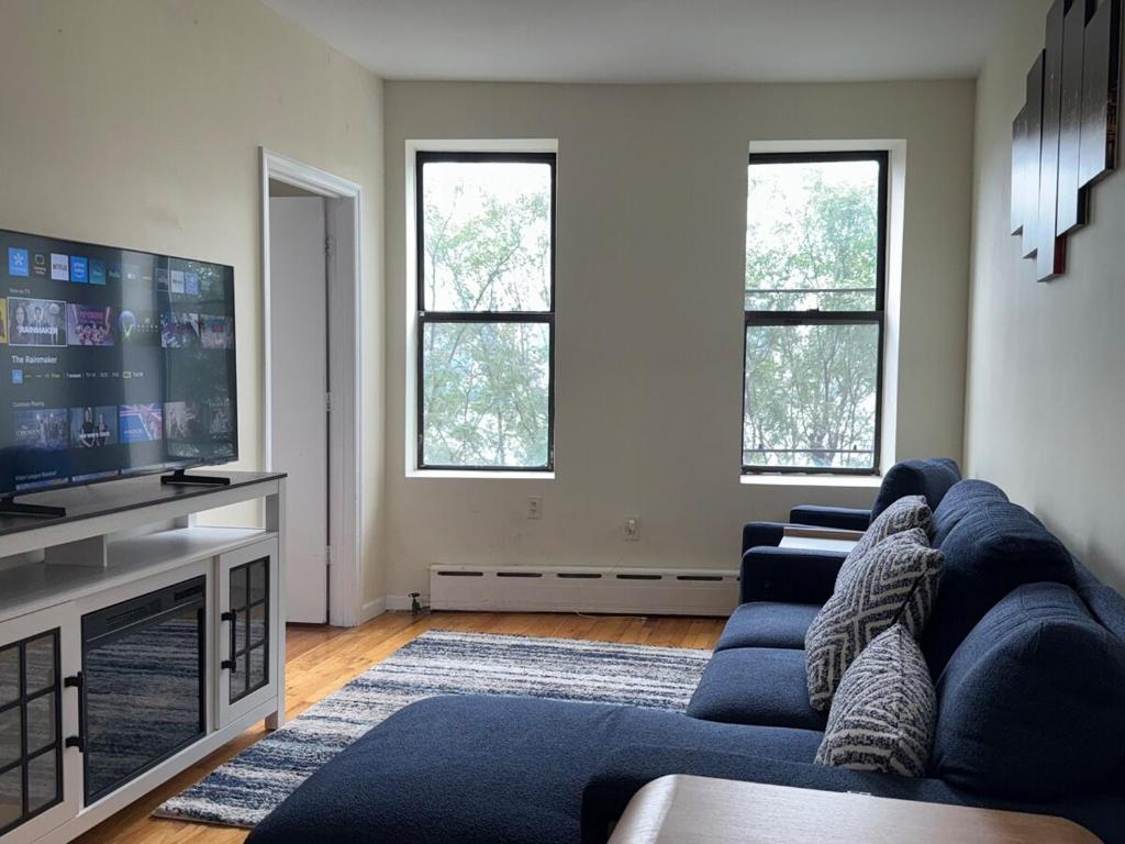 a living room with a blue couch and a tv at Weehawken Apartment NYC Skyline in Weehawken