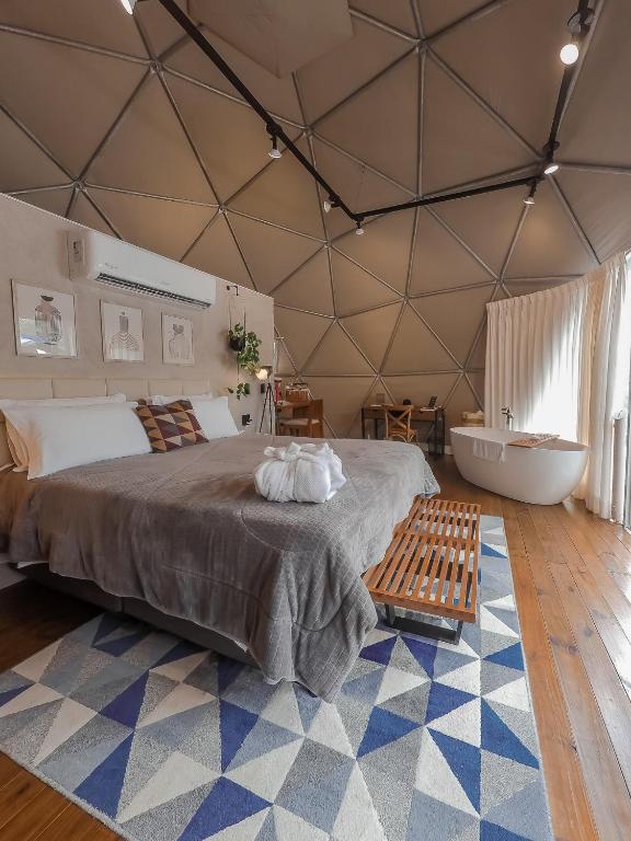 a bedroom with a large bed and a bath tub at GOAT LODGE Domo Pitanga in Ibiúna