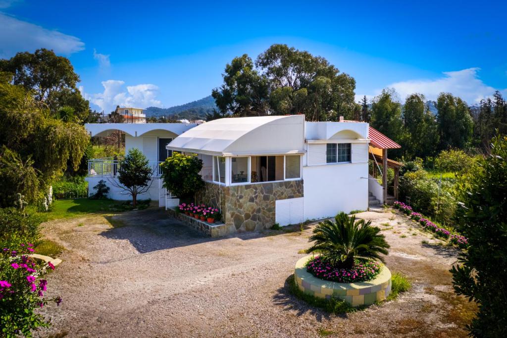 a white house with an awning in a yard at Flora Beach House in Kremasti