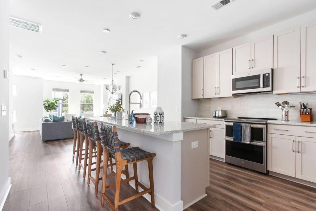 a kitchen with white cabinets and a bar with stools at The Trendy In Park Circle Mins to DT CHS & Beach in Charleston