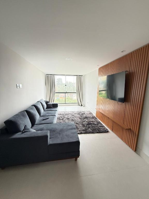 a living room with a black couch and a flat screen tv at Recanto da Praia in Anchieta
