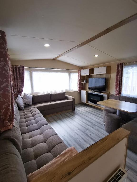a living room with a couch and a table at Willows Lodge with self contained garden in Carlisle