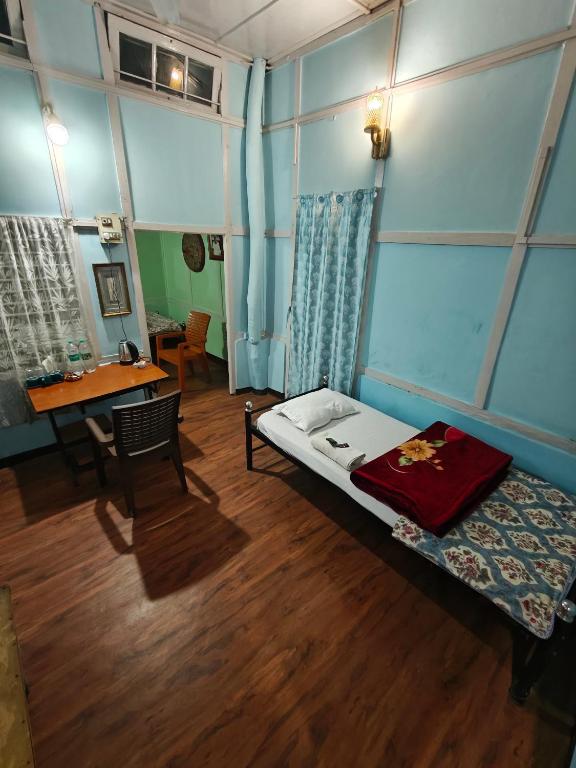 a room with a bed and a table and a desk at Hemalata Heritage Home in Guwahati