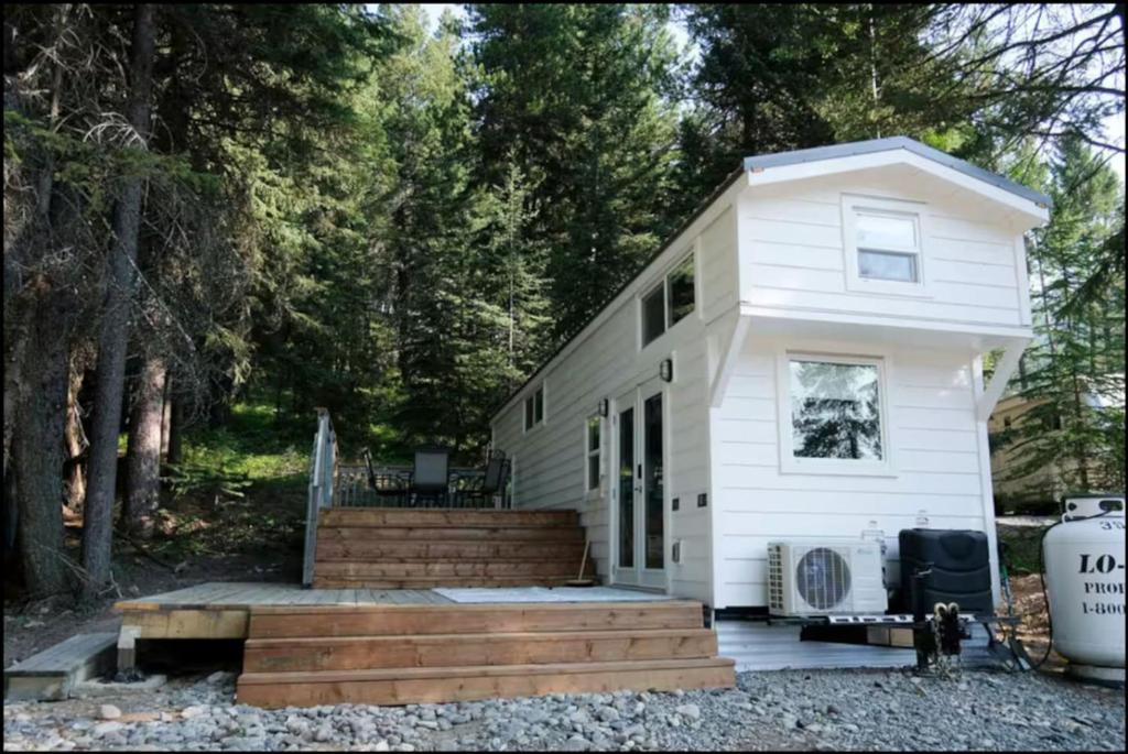 a white tiny house with a porch and stairs at Lilys Little Lodge in Blairmore