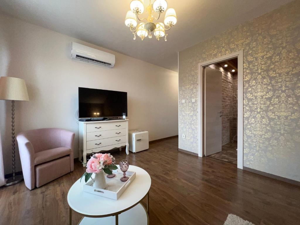 a living room with a table and a tv at Gold Horse Vendégház in Szilvásvárad