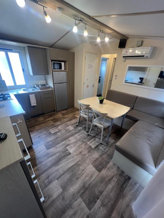 a living room with a table and a kitchen at Les mobil homes de NOLY TV CLIM 6places 1 place adulte offerte pour la réserve africaine sigean in Port-la-Nouvelle