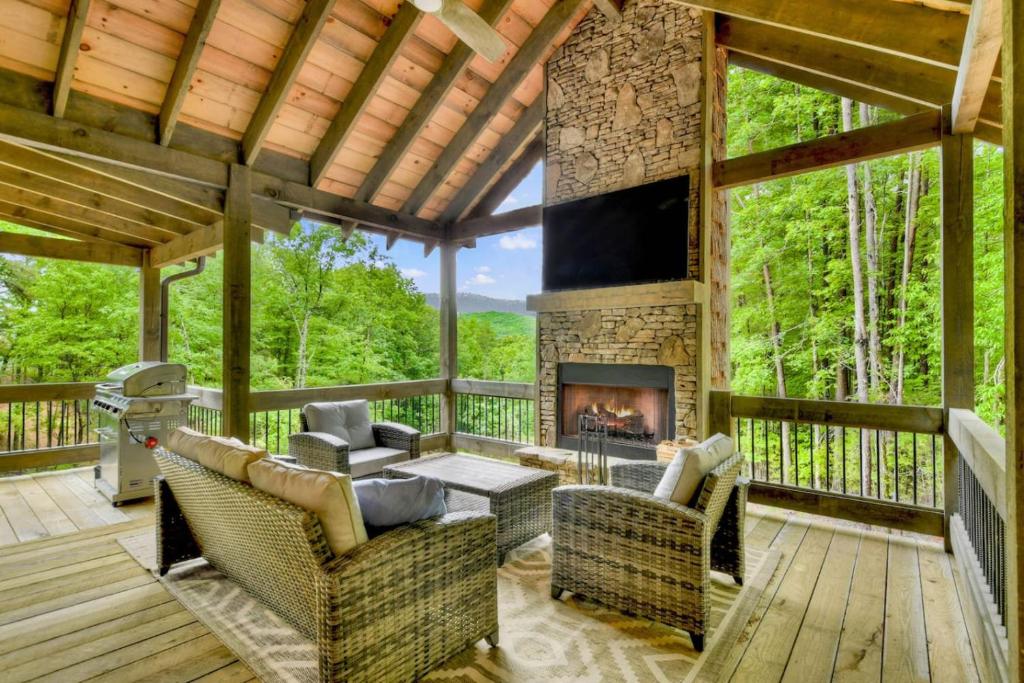 a screened in porch with a fireplace on a deck at Altitude Adjustment- Luxury 3BR Cabin w/ Outdoor Living Area & Hot Tub in Epworth