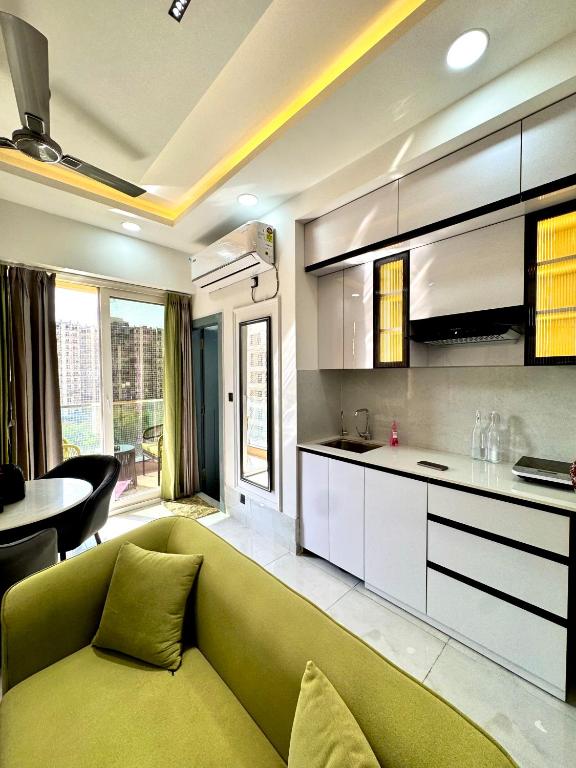 a living room with a green couch and a kitchen at Lux Lettings in Noida