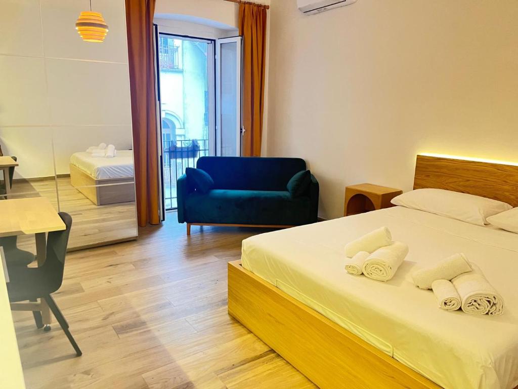 a bedroom with a bed and a blue chair and a desk at casa vacanza La Palma Rossa Taranto in Taranto