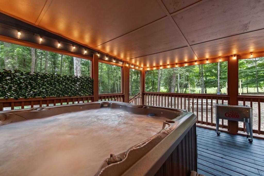 a large hot tub on a deck with trees at The Racoons Nest in Copperhead Lodge in Blairsville