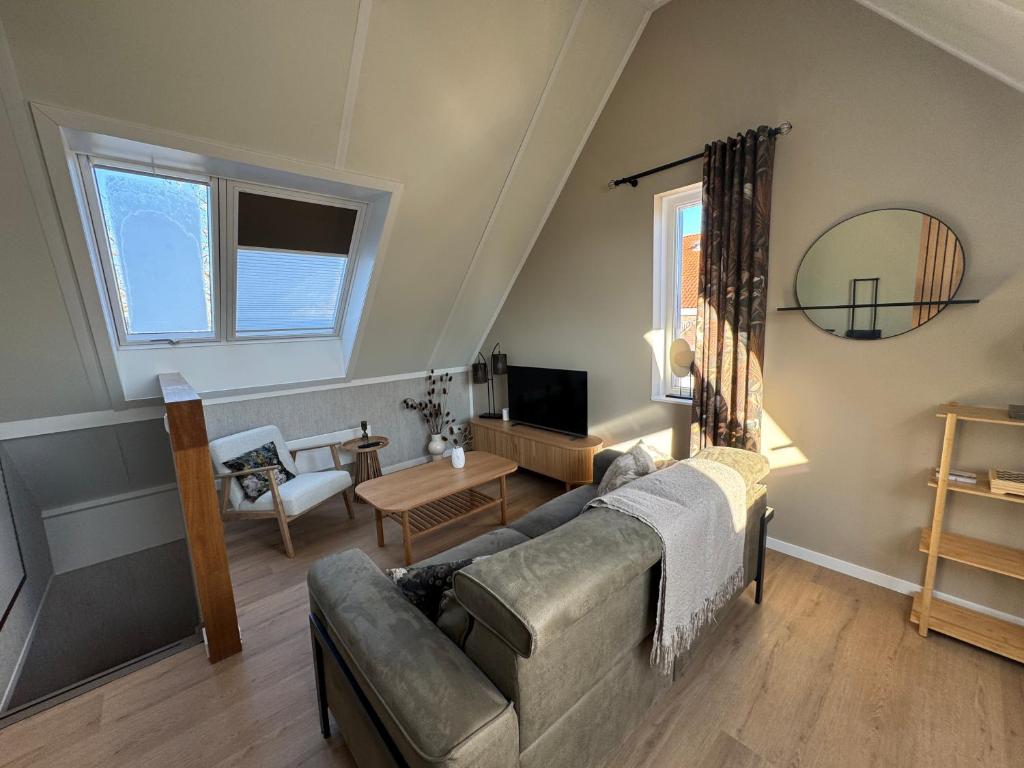 a living room with a couch and a tv at Kustgeluk-Luxe aan Zee, splinternieuw appartement in het hart van Koudekerke in Koudekerke