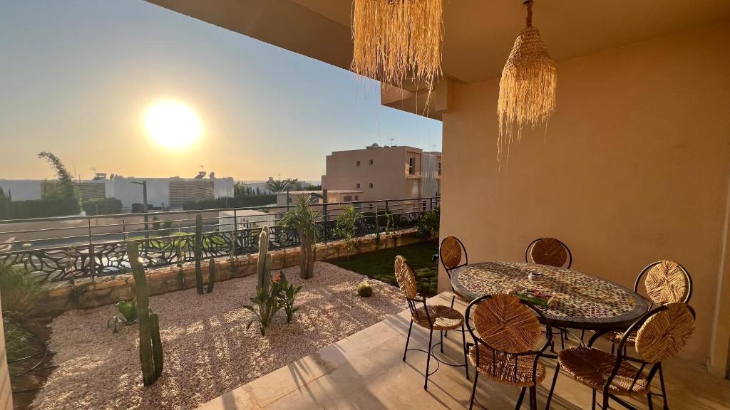 a patio with a table and chairs on a balcony at Strandwohnung Taghazout mit Meerblick, Terrasse, Garten & Pool 2 Min zum Surfspot in Taghazout