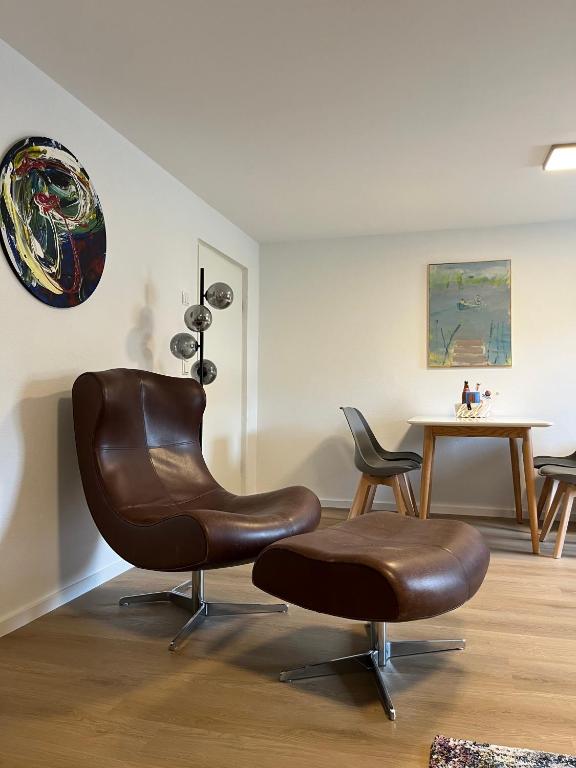 a brown leather chair in a room with a table at ammersee apARTment Dießen in Dießen am Ammersee