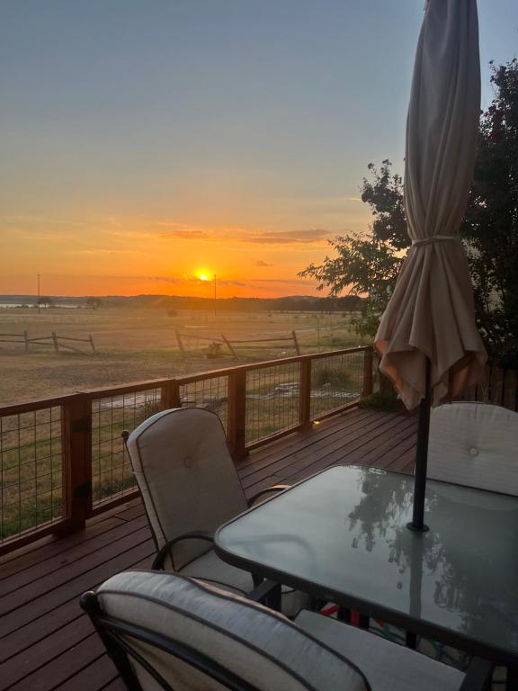 a table and chairs on a deck with an umbrella at Lakeside Sunset - Hot Tub, Pool Table, Beautiful Views!! in Canyon Lake