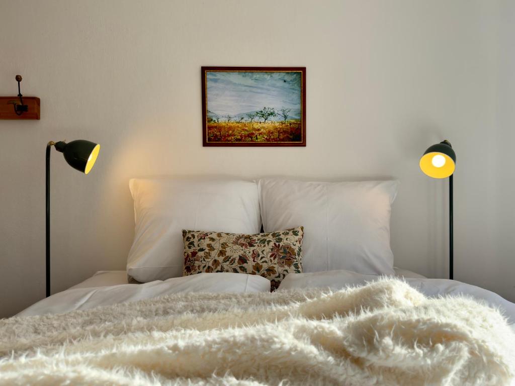 a bedroom with a white bed with two lamps at Haus zum Ordenswald in Neustadt an der Weinstraße